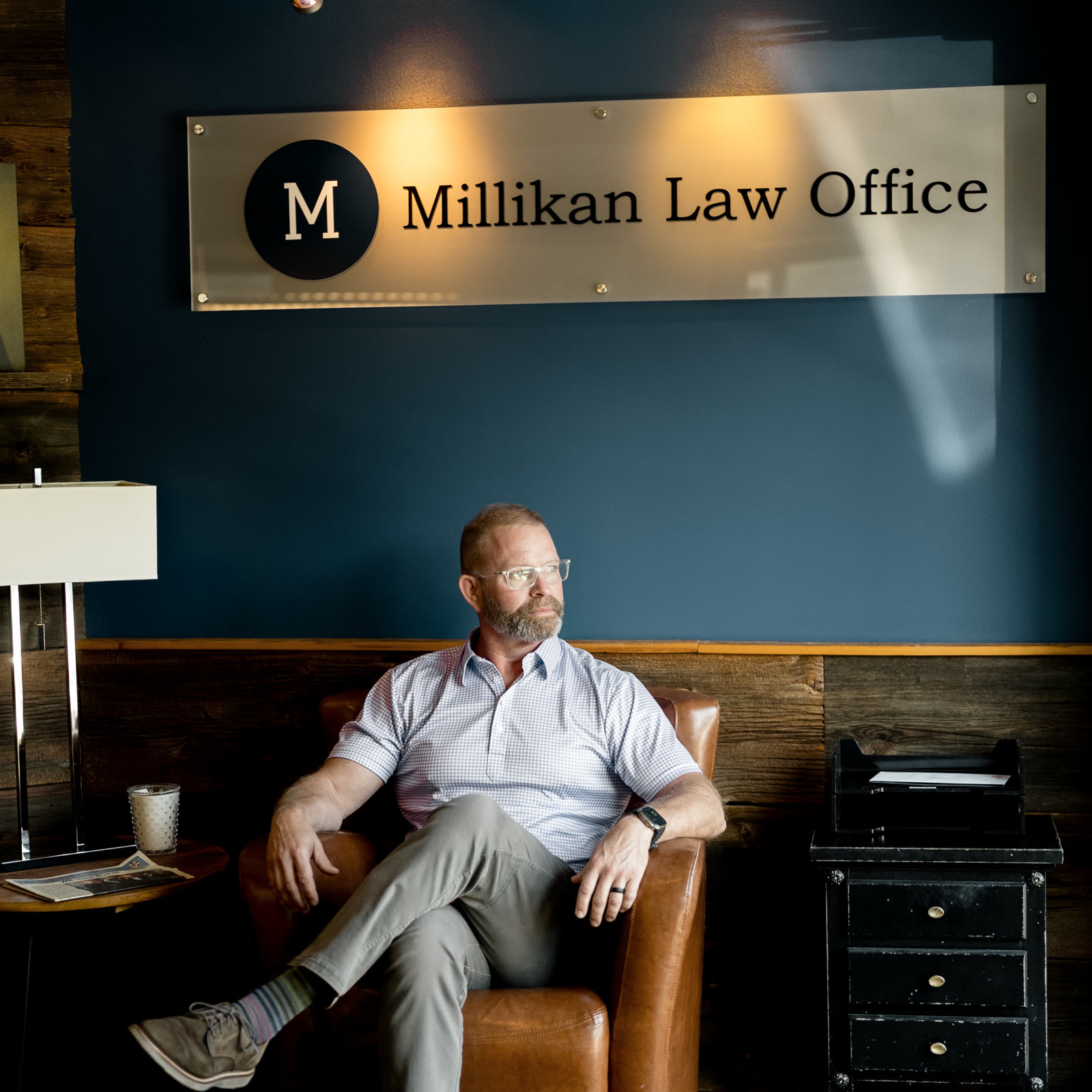 Brian P. Millikan seated beneath the Millikan Law Office sign in the Kirkwood office