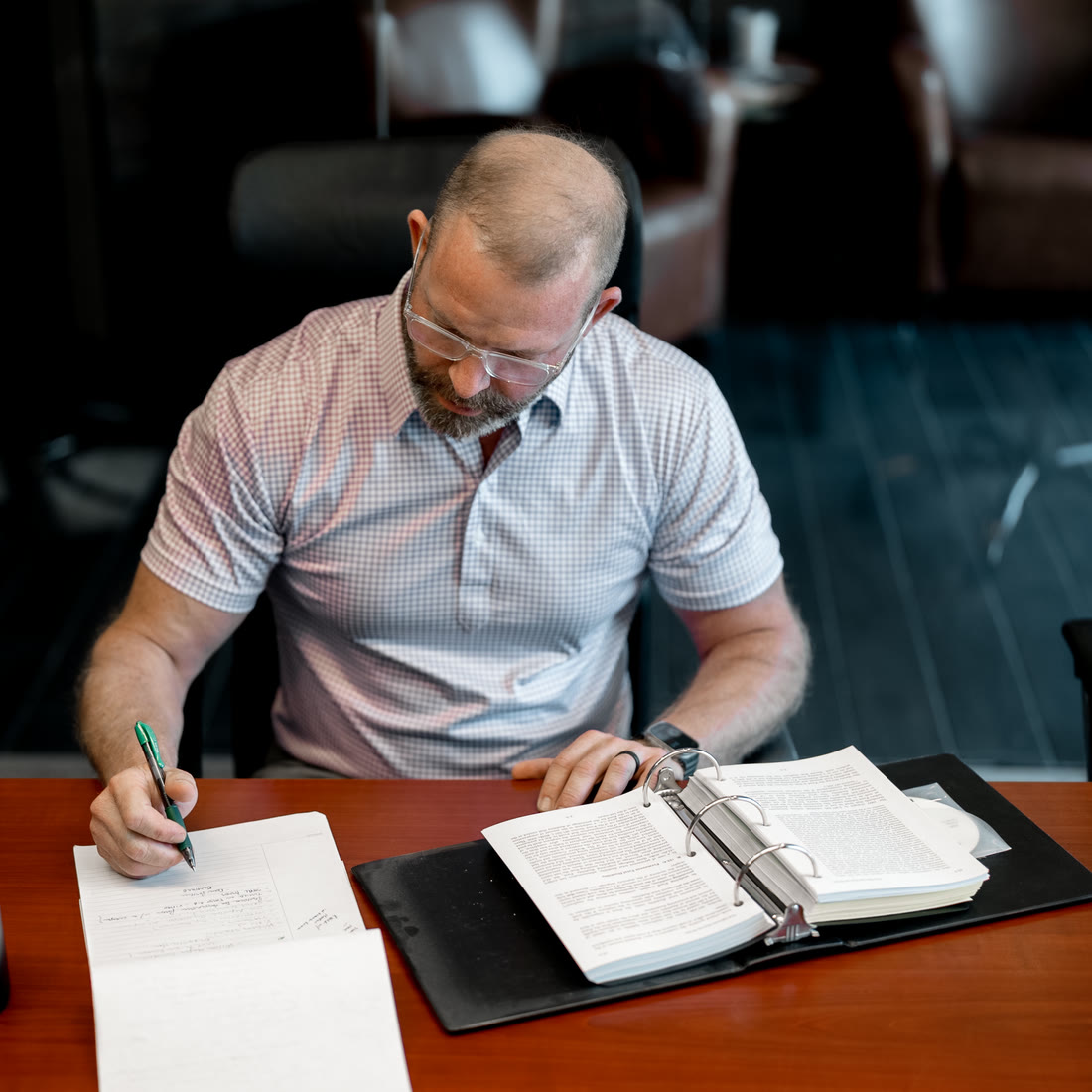 Brian Millikan at the conference table in the Kirkwood office, writing notes beside an open binder